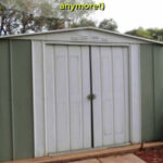 Green and white garden shed with sliding doors. Text overlay says: How to Fix Broken Shed Doors (when the doors won’t slide anymore!).