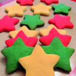 Star shaped cookies coloured white, red, and green on a silicone baking mat.