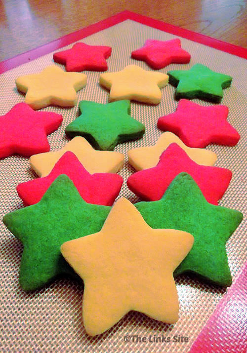 Star shaped cookies coloured white, red, and green on a silicone baking mat.