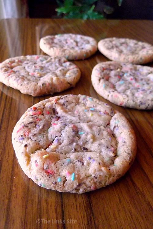 Five cake mix cookies on a wooden table, one is placed front and centre and the others are in the background.