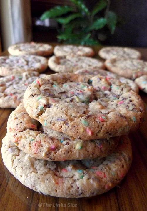 Three cake mix cookies are stacked in the foreground and several more are arranged in a single layer the background.