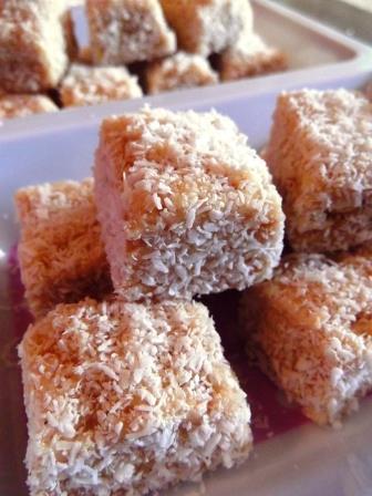 Lemon coconut squares stacked in a bowl.