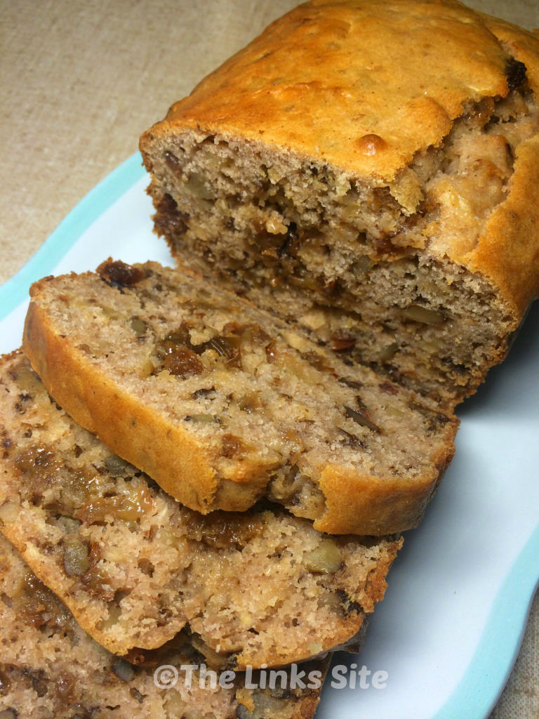 Walnut raisin loaf on a white and blue plate. Several slices have been cut from the loaf and are lying next to the main loaf.
