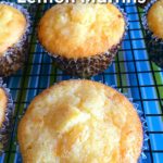 Overhead shot of a lemon muffin surrounded by more lemon muffins, all sitting on a cooling rack on a blue and green striped tablecloth. Text over lay on image says Lemon Sour Cream Muffins.