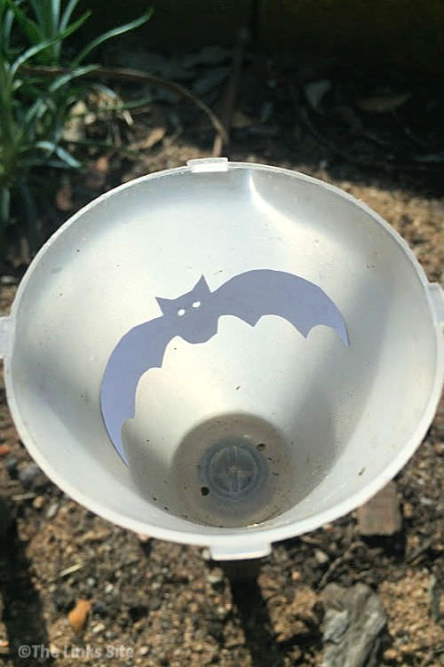 Image looking down inside the top of a solar light. A cut out bat picture is stuck to the inside of the light.