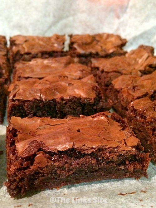 Rows of brownies arranged on baking paper.