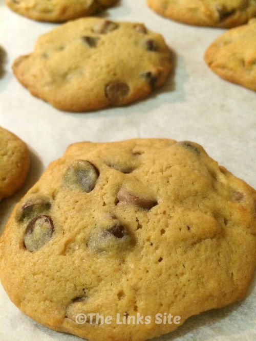 Several caramel chocolate chip cookies are arranged on baking paper.