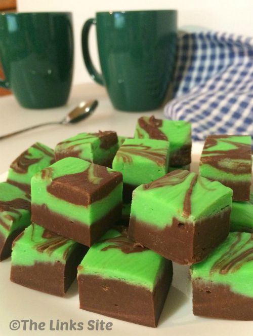 Squares of chocolate and mint fudge. The top layer of fudge is bright green and has been swirled with chocolate.