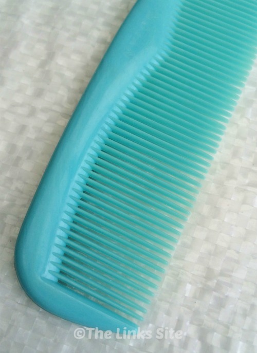 Close up of a light blue plastic hair comb with a white background.