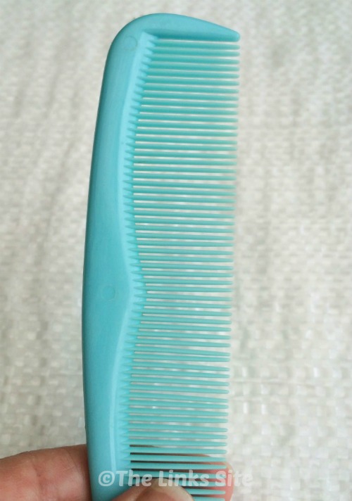 Blue plastic hair comb with a white background. A finger and thumb can be seen holding the comb.