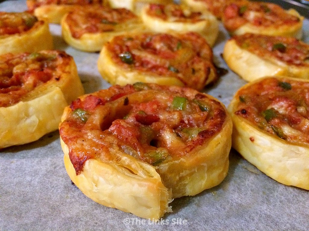 Freshly baked pizza pinwheels on a baking tray.