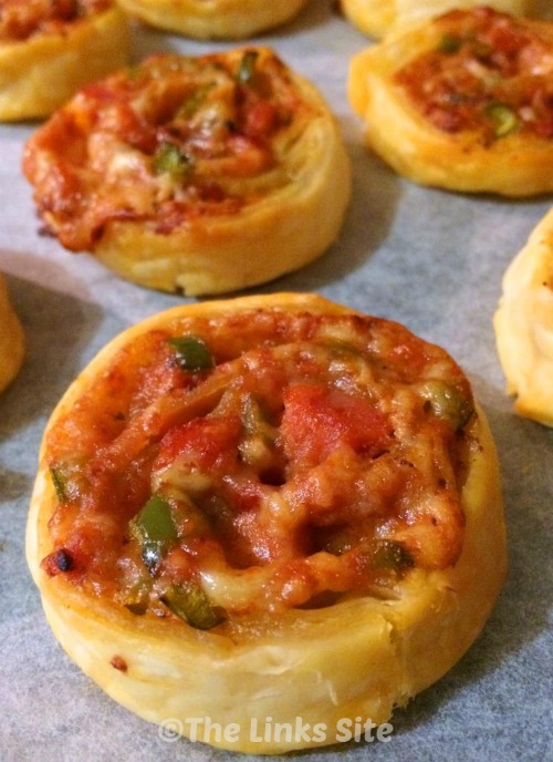 Pizza pinwheels on a lined baking tray.
