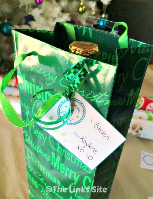 Green, Christmas themed, wine gift bag with a gift tag attached.
