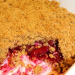 White baking dish containing plum crumble. Some of the crumble has been spooned out of the dish.