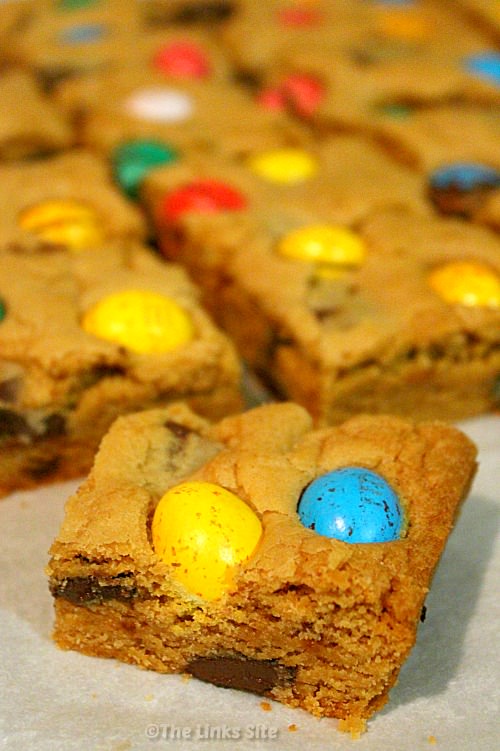 A cookie bar topped with a yellow and a blue speckled chocolate egg. More cookie bars can be seen in the background.