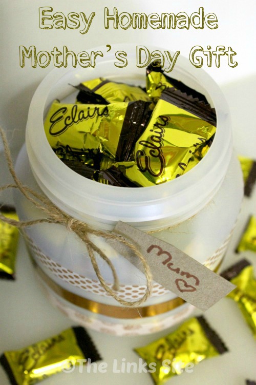 Looking down into the top of a plastic container that is filled with Éclair lollies. The container is decorated with washi tape and extra lollies are scattered around the outside. A gift tag address to Mum is attached with twine. Text overlay says: Easy Homemade Mother’s Day Gift.