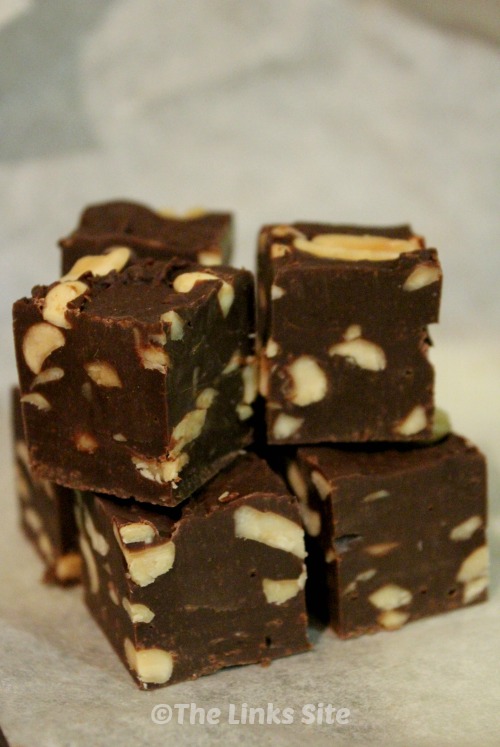 Pieces of peanut fudge stacked up on a piece of baking paper.