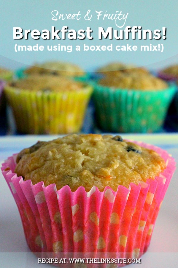 One muffin in a pink and white spotted paper case is in the foreground. A plate containing more muffins can be seen in the background. Text overlay says: Sweet & Fruity Breakfast Muffins (made using a boxed cake mix!).