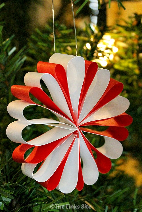 A red and white paper Christmas decoration hanging from a Christmas tree.