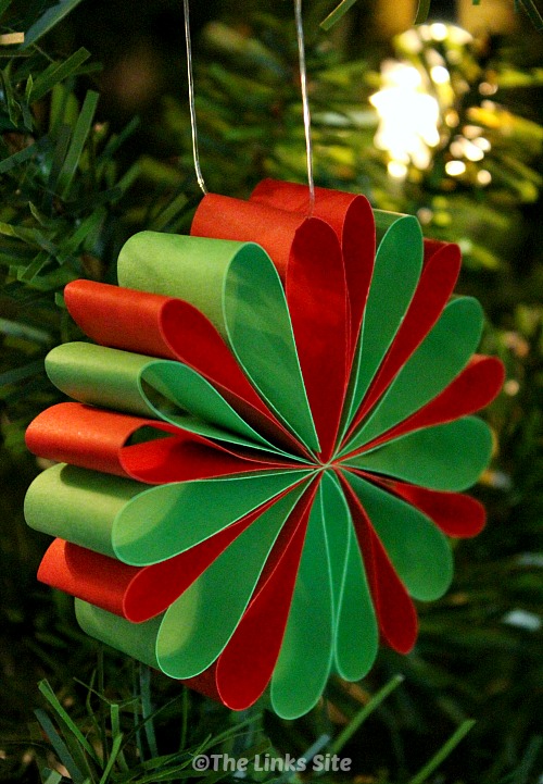A red and green paper decoration hanging in a Christmas tree.