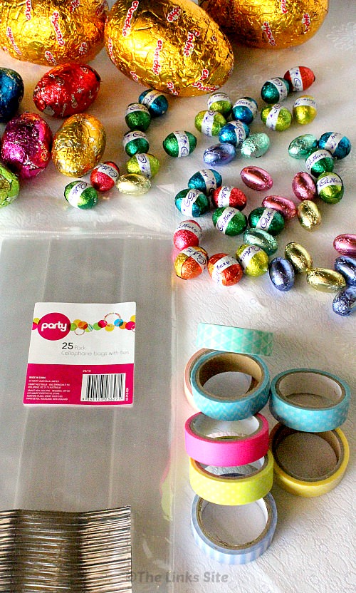Project materials are laid out; including Easter eggs, cellophane bags with ties, and washi tape.