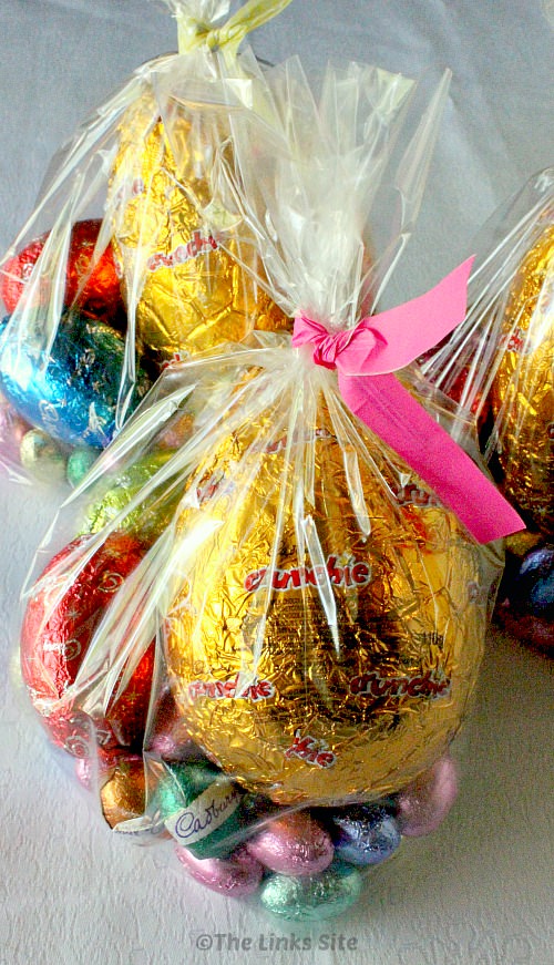 Plastic goodies bags are filled with Easter eggs of different sizes and closed at the top with a coloured twist tie.
