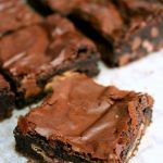 One chocolate mint brownie on baking paper with more brownies in the background.