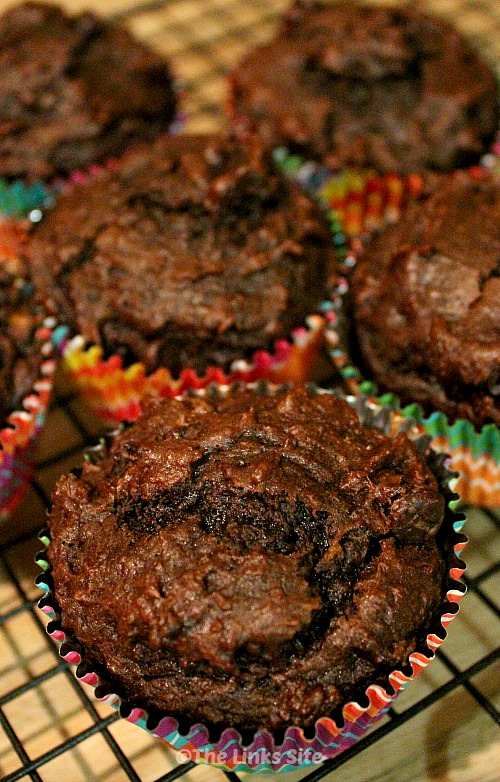 Several chocolate pumpkin muffins on a black cooling rack.