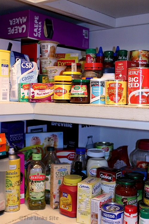 Two shelves of a pantry that are stocked with food items.