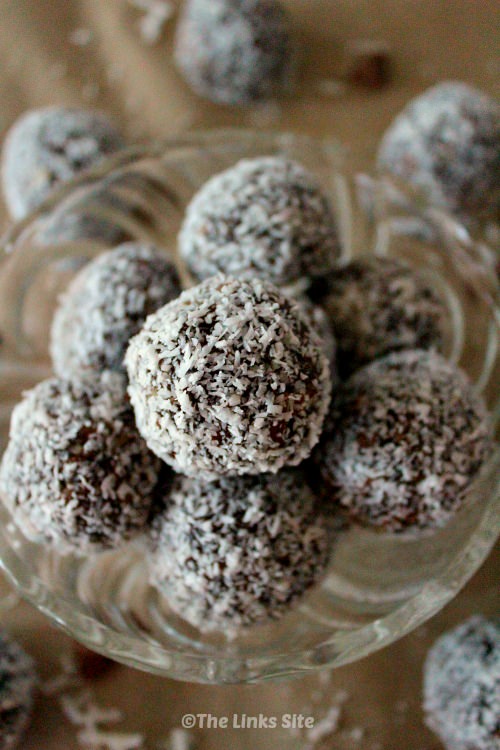 Small group of energy balls in a glass bowl with more balls around the bowl.