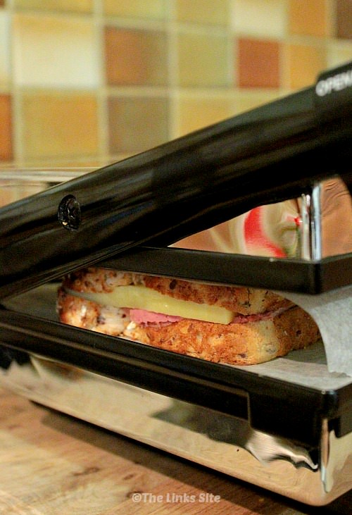 Ham and cheese sandwich being toasted in a sandwich press.