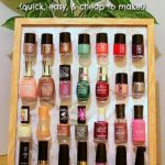 Photo frame with light wooden edge sitting on a bench with a potted plant in the background. Four rows of seven nail polish bottles are stuck to the photo frame. Text overlay states: DIY Nail Polish Organizer (quick, easy, and cheap to make!).