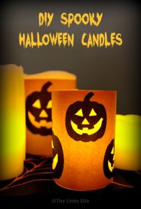 A dimly lit image showing battery powered pillar candles wrapped with orange craft paper that is decorated with Jack O Lantern faces. The facial features have been cut out so that the light from the candles shines through. Text overlay says: DIY Spooky Halloween Candles.