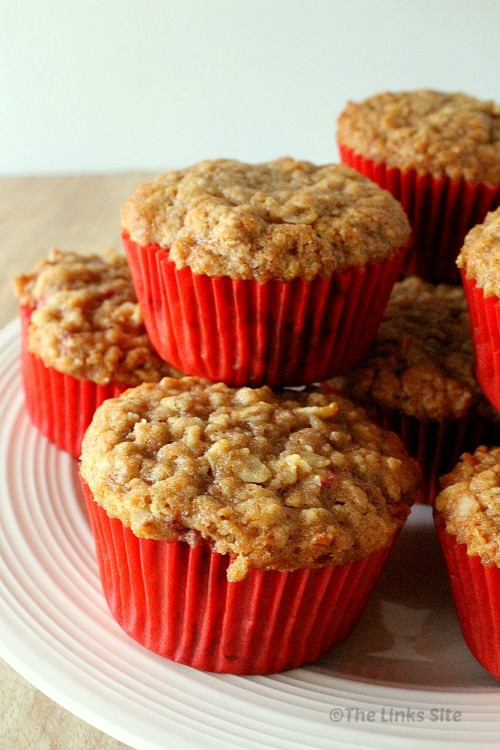 Close up showing several strawberry oat muffins stacked on white plate.