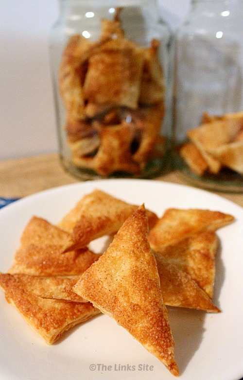 White plate topped with several cinnamon sugar puff pastry triangles. Glass jars filled with more puff pastry pieces can be seen in the background.