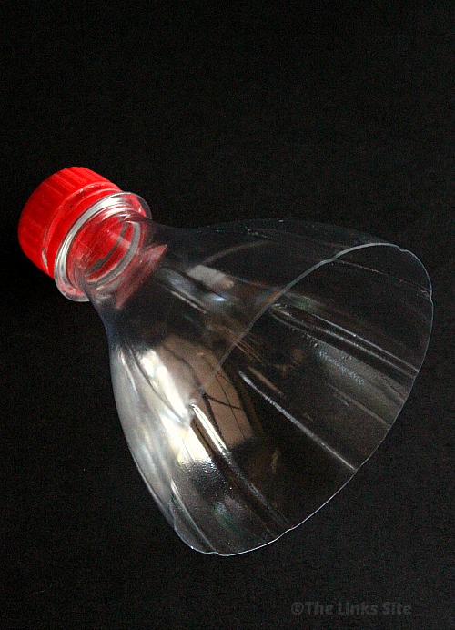 Neck portion of an empty soda bottle on a black background.