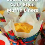 Several muffins on a white plate with multi coloured spots. Each muffin is in a baking paper liner and then an outer liner made from multi coloured wrapping paper. Curling ribbon is tied around the muffins for decoration. Text overlay says: Make Your Own Customisable Café Style Muffin Liners.