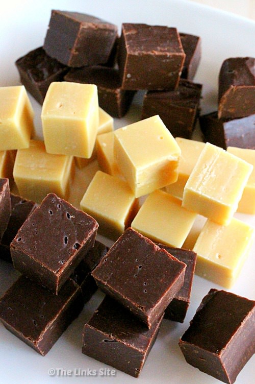 Three types of 2 ingredient fudge piled onto a white plate. Chocolate fudge in foreground, caramel fudge in the middle and choc caramel fudge in the background.