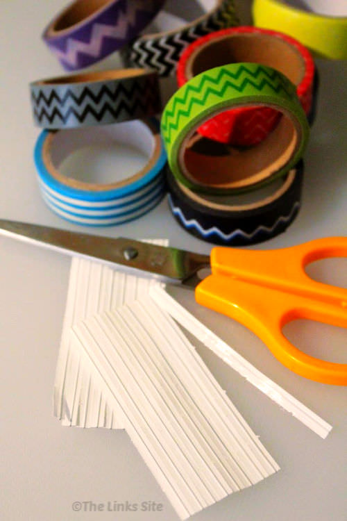 White plastic coated twist ties, a pair of scissors, and several rolls of washi tape on a white surface.