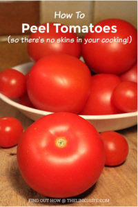A bowl of ripe red tomatoes of various sizes on a wooden cutting board. A couple of tomatoes are placed on the board in front of the bowl. Text overlay says: How to Peel Tomatoes (so there’s no skins in your cooking!).
