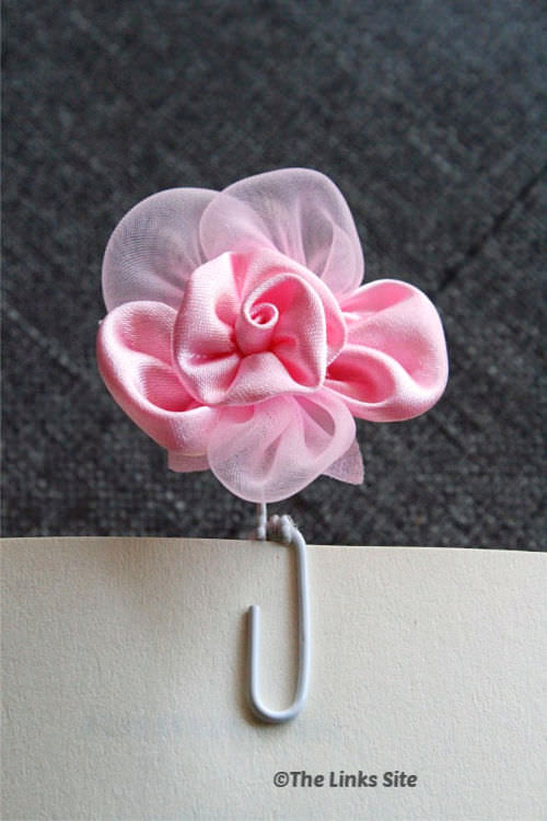One bookmark attached to the top of a book. The bookmark is white with a pink flower. 