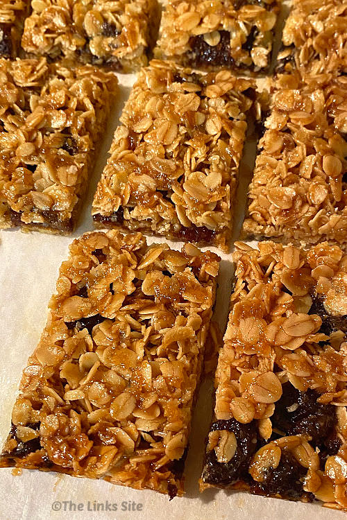 Several flapjacks are arranged in rows on a piece of baking paper.
