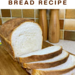 Loaf of white bread on a wooden cutting board with some slices cut. Text overlay says: Simple Homemade Bread Recipe.