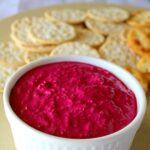 Beetroot Dip in a bowl with crackers in the background.