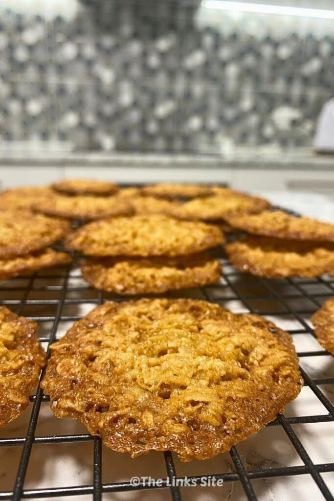 Close up of one rolled oat biscuit on a wire rack with more biscuits in the background.