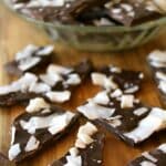 Pieces of dark chocolate coconut bark on a wooden board.