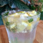Virgin mojito in a glass on a wooden board. Green plants are seen in the background.