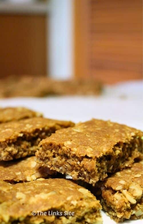 Pieces of Nutty Oat Slice stacked in two layers on baking paper.