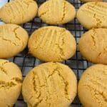 Golden syrup cookies cooling on a black wire rack after baking.