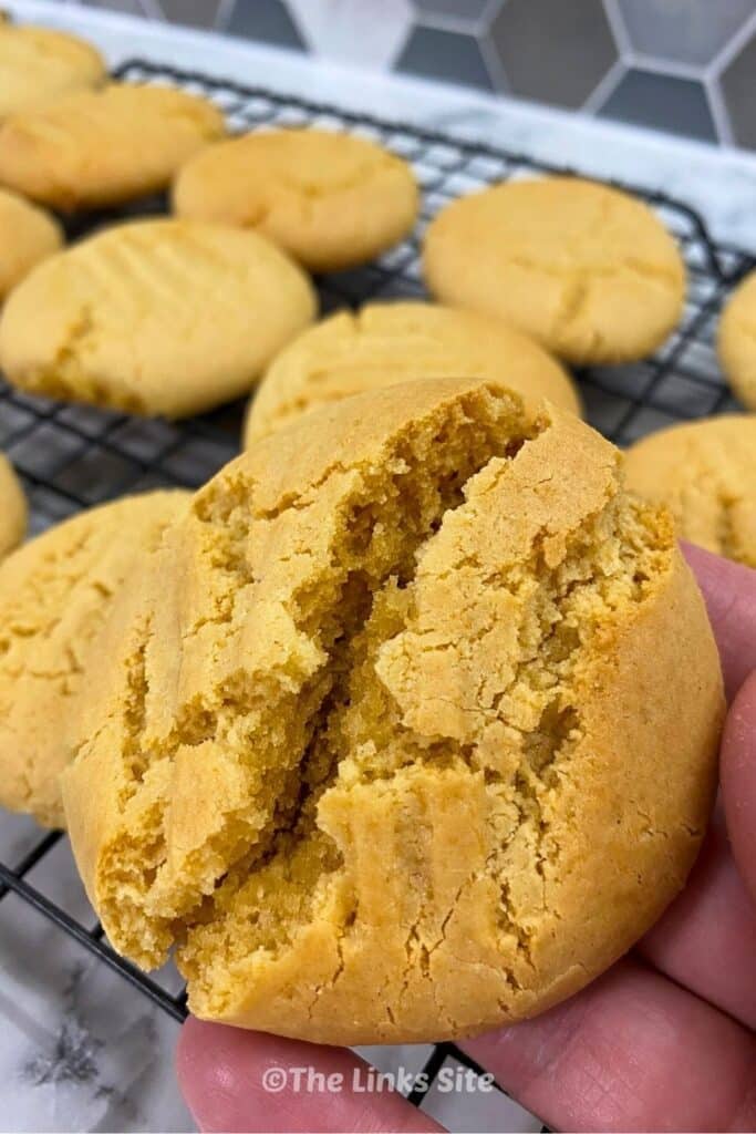 Golden syrup cookie split open in a hand, revealing its soft centre.